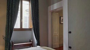 A bedroom with a bed, a window with curtains, a door, and a light fixture on the ceiling. - Pergola One Romantic Apt by Oteego (Florence)