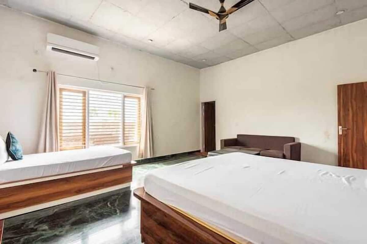 A hotel room with two beds, a wooden headboard, a ceiling fan, and a window with blinds.