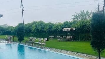 Relax by the serene pool surrounded by lush greenery and comfortable lounge seating.