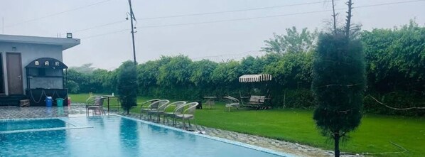A swimming pool with lounge chairs and a bar area. - Evergreen Resort & Farm Aravali (Gurugram)