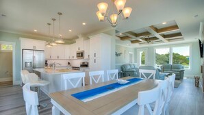 Une cuisine spacieuse avec des meubles blancs, un îlot central et des luminaires suspendus.