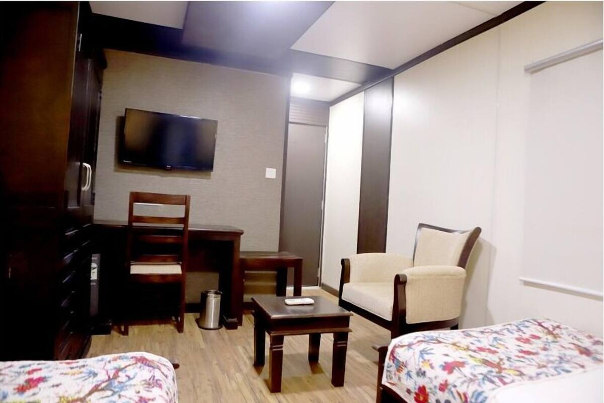 Una habitación de hotel con una cama, un escritorio, una silla, un televisor y un armario.