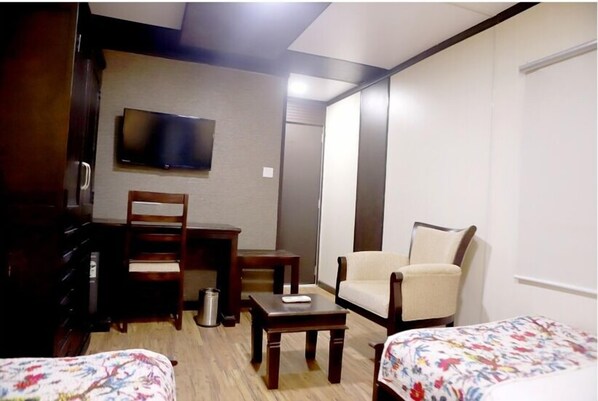 A hotel room with a bed, a desk, a chair, a TV, and a wardrobe. - Kiri Container Resorts (Gudhamalani)