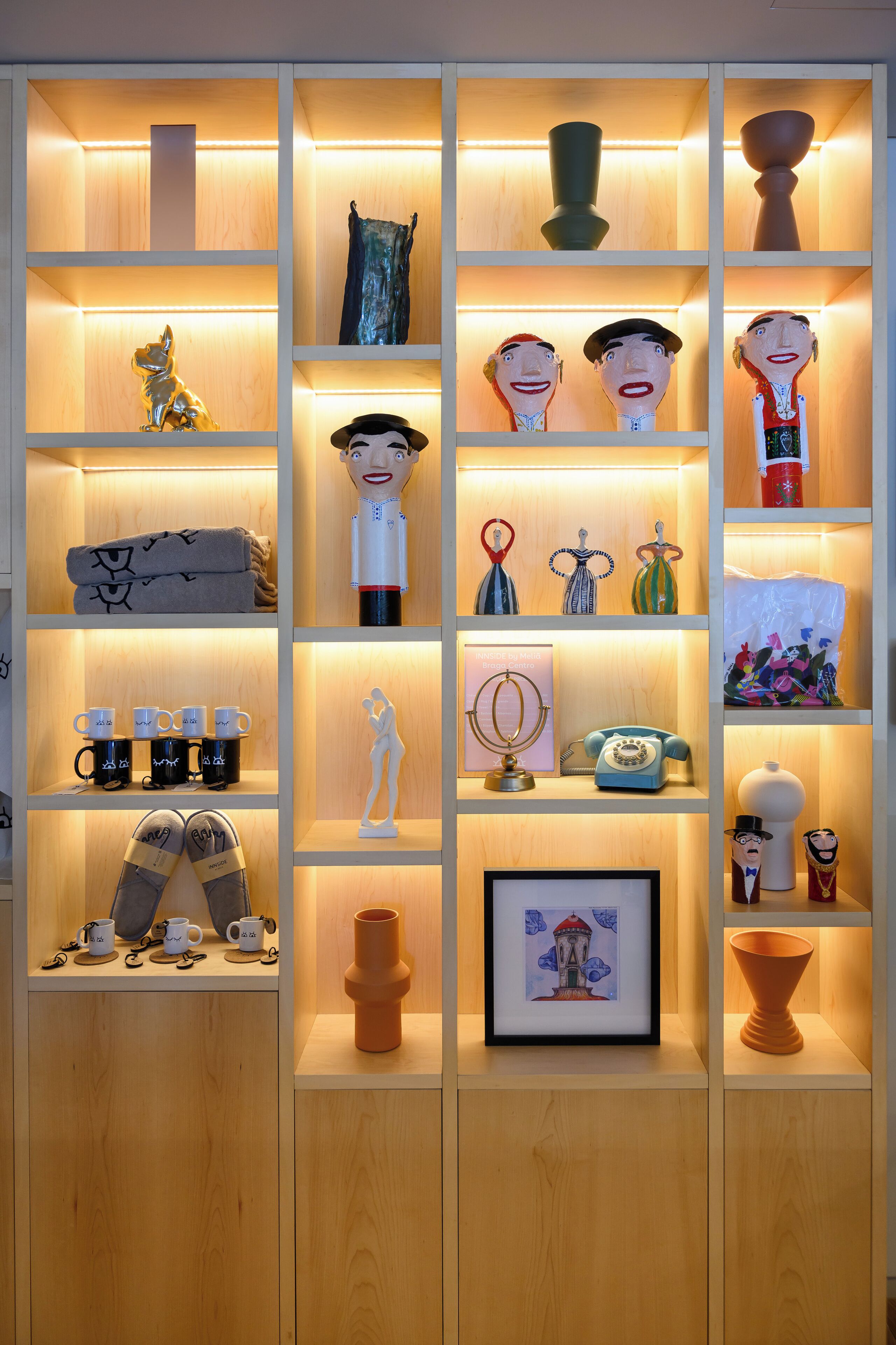 A wooden display cabinet with various decorative items including figurines, mugs, and a vintage telephone.