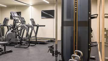 Une salle de sport équipée de machines de musculation, de tapis de course et de vélos d’exercice.