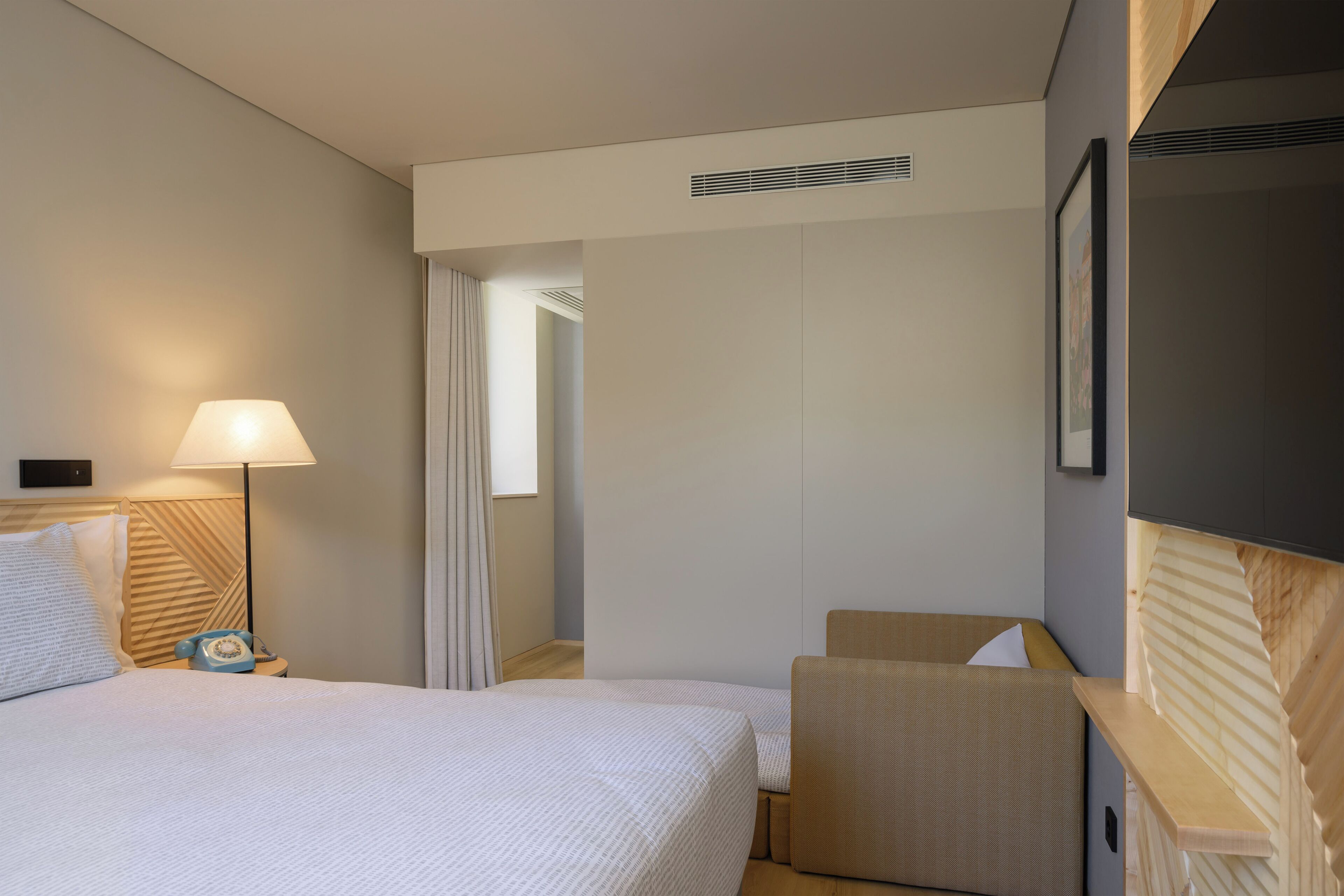 A hotel room with a bed, bedside lamp, and a chair.