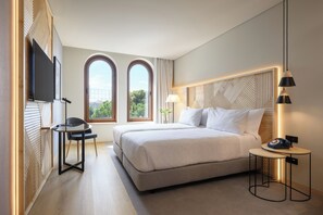 A modern hotel room with a large bed, a desk, a chair, and a TV mounted on the wall. - INNSiDE By Meliá Braga Centro (Braga)