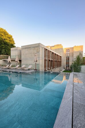 A modern pool area with clear blue water, lounge chairs, and umbrellas. - INNSiDE By Meliá Braga Centro (Braga)