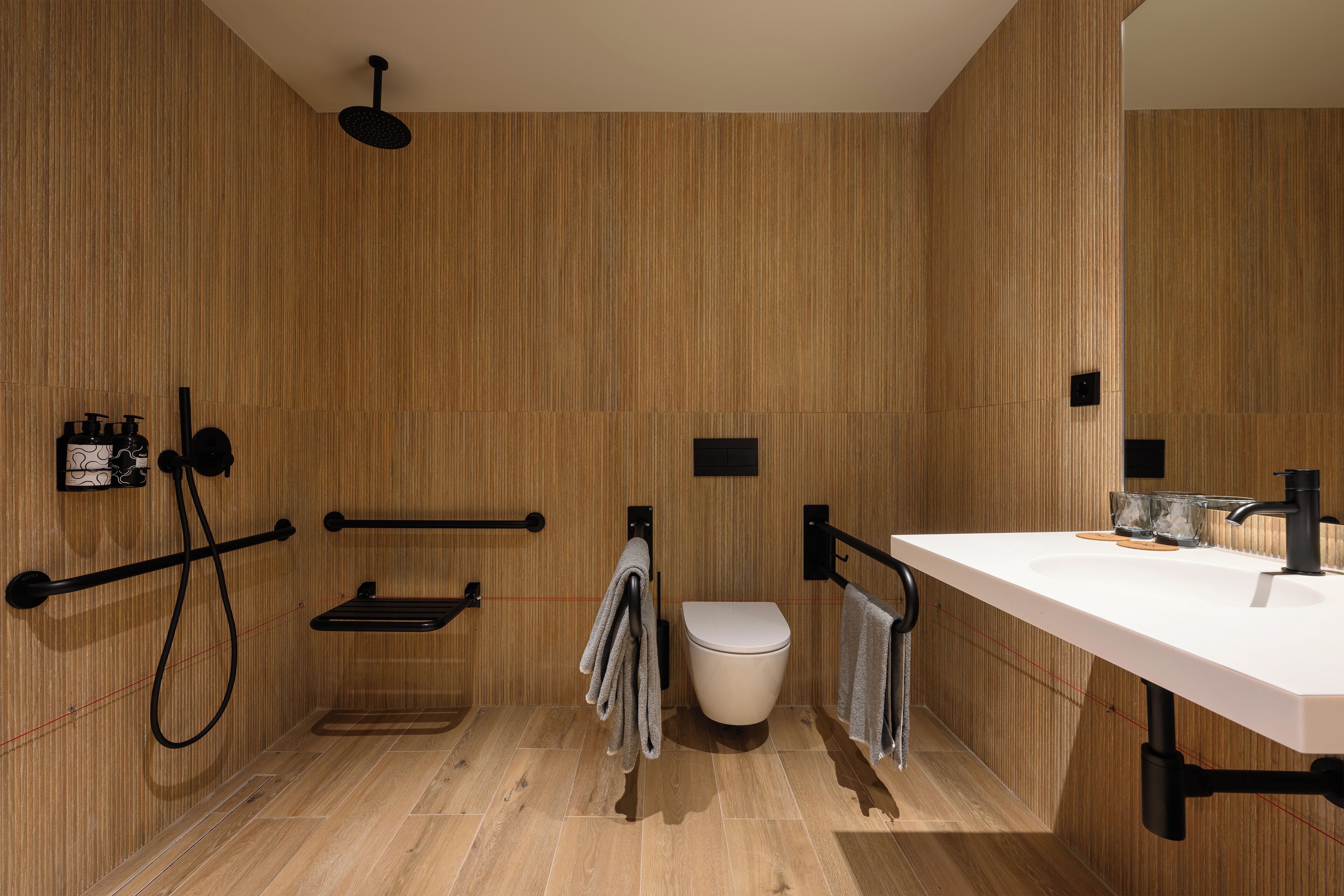 A modern bathroom with a wooden wall design, a white sink, and a toilet.