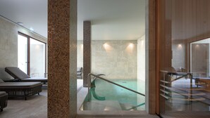 A modern spa area with a glass-enclosed hot tub, cushioned seating, and a staircase leading to an upper level. - INNSiDE By Meliá Braga Centro (Braga)