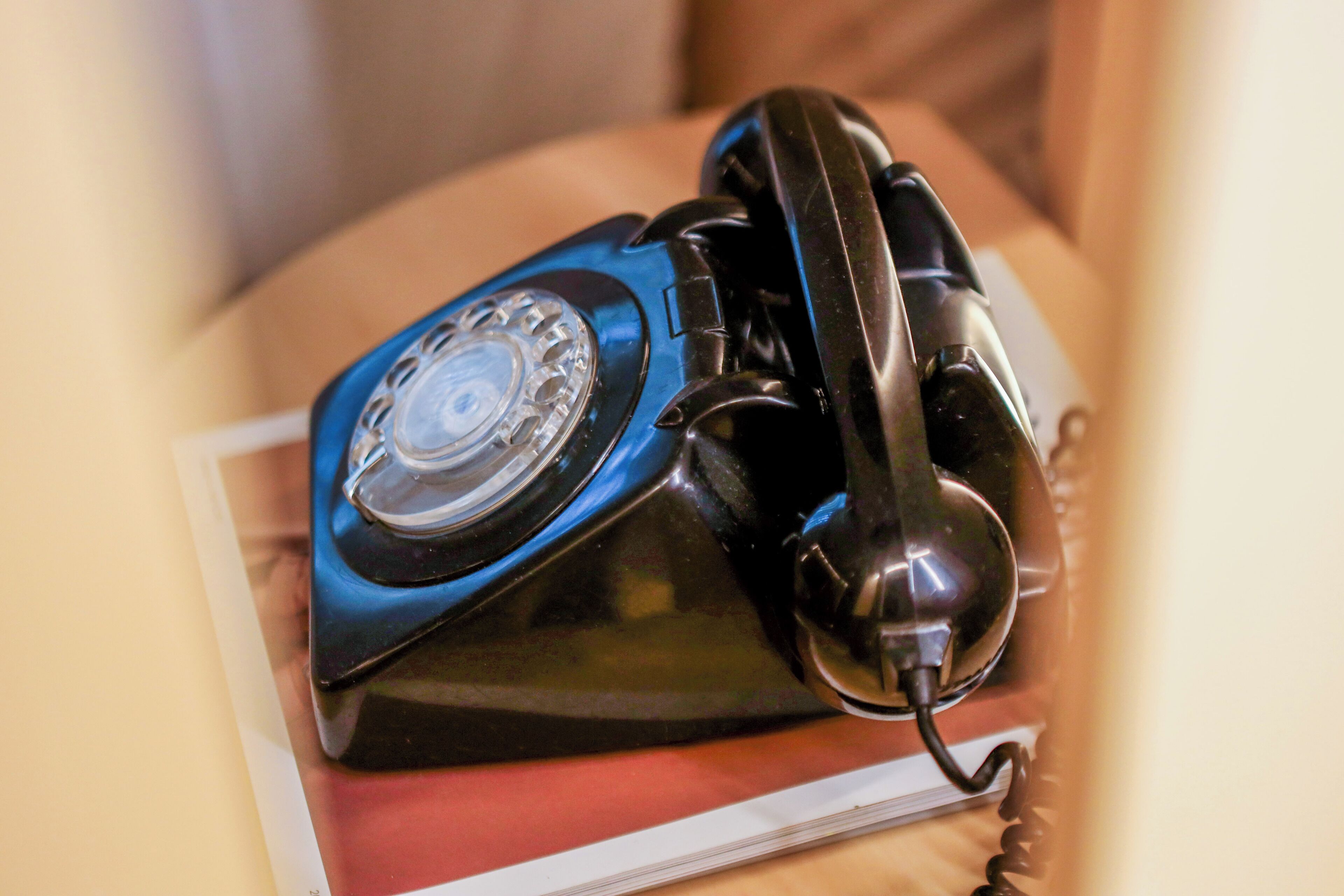 Ein blaues Wählscheiben-Telefon auf einem roten Buch.