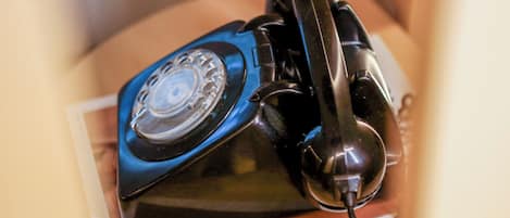 Ein blaues Wählscheiben-Telefon auf einem roten Buch.