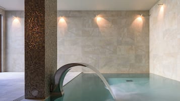 Relax in a serene spa area featuring a large hot tub and mosaic tile accents.