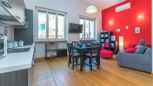 A modern kitchen with a dining area, a red accent wall, and a grey sofa. - Casa Boccaccio by Wonderful Italy (Turin)