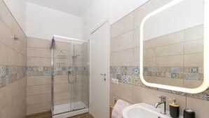 Un baño con ducha, lavabo y espejo.