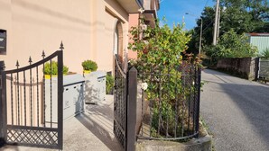 Una calle residencial con entrada porticada, un edificio rosa y un pequeño jardín con rosales.
