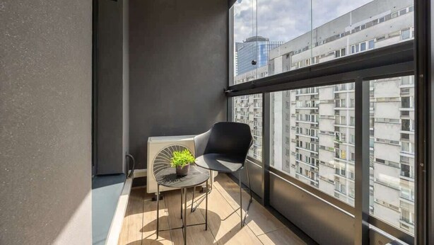 Ein Balkon mit Stuhl, Tisch und einer Topfpflanze.