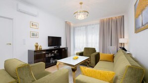 Ein modernes Wohnzimmer mit einer Sofagarnitur, einem Couchtisch, einem Fernseher und einer Pendelleuchte.