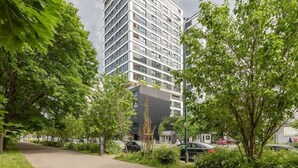 Ein modernes Gebäude mit Glasfassade, umgeben von üppigem Grün und einem gepflasterten Weg.