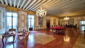 Una habitación amplia con alfombra roja, candelabros ornamentados y mobiliario clásico.