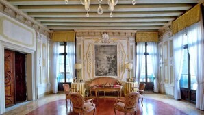 Una sala amplia con un gran tapiz rojo, muebles ornamentados y un candelabro.