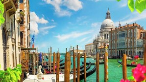 Un canal con góndolas, un edificio histórico con cúpula y una hilera de edificios venecianos tradicionales.