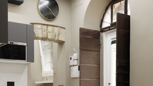 A modern kitchen with a built-in microwave, a wooden dining table, and a clock on the wall. - Unique Trastevere (Roma)