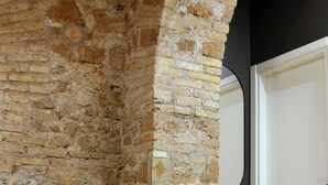 A room with a stone wall, a door, and a wooden floor. - Unique Trastevere (Roma)