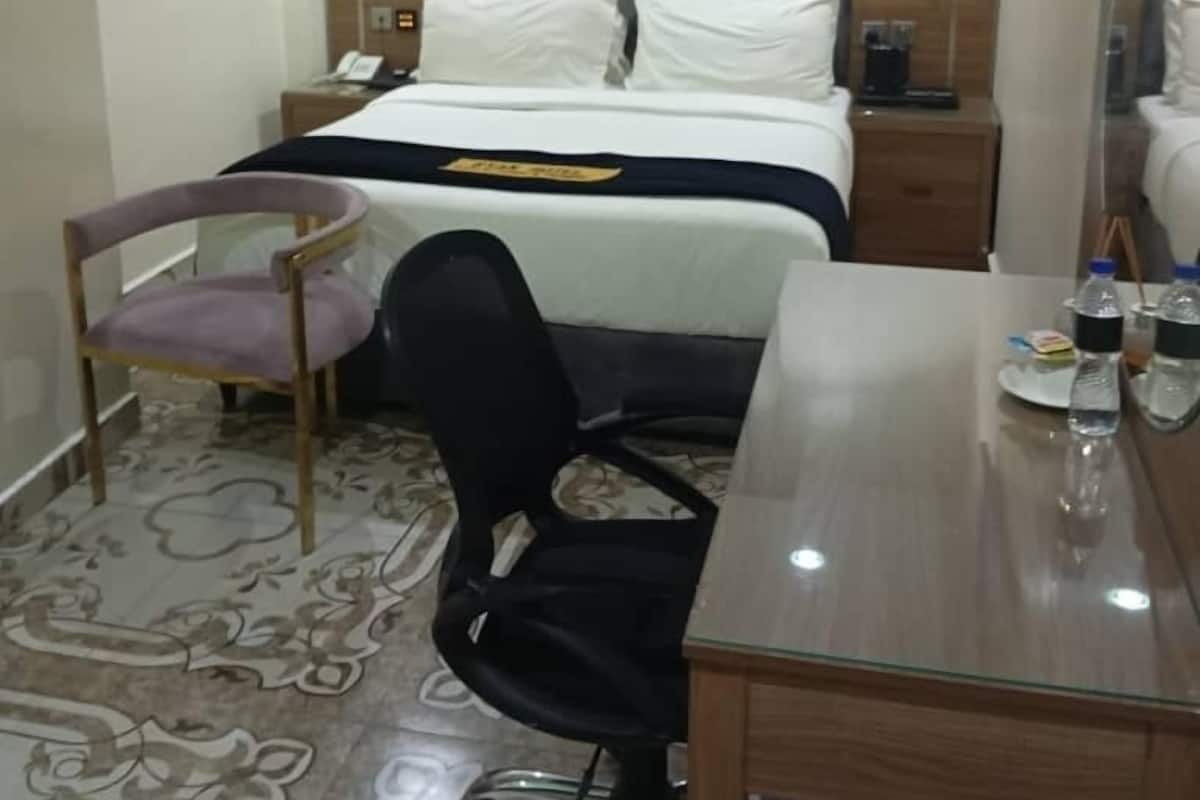 Een hotelkamer met een bed, een bureau, een stoel, een spiegel en een airconditioning.