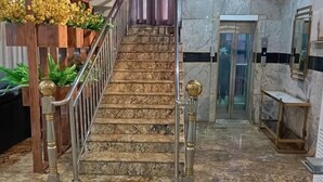 Eine Marmortreppe mit Metallgeländer und dekorativen Elementen, die zu einer Tür mit Glasfenster führt.