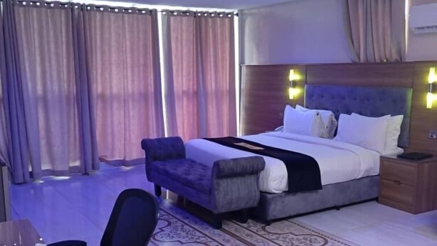 Ein Hotelzimmer mit Bett, Schreibtisch, Stuhl und einem gemusterten Teppich.