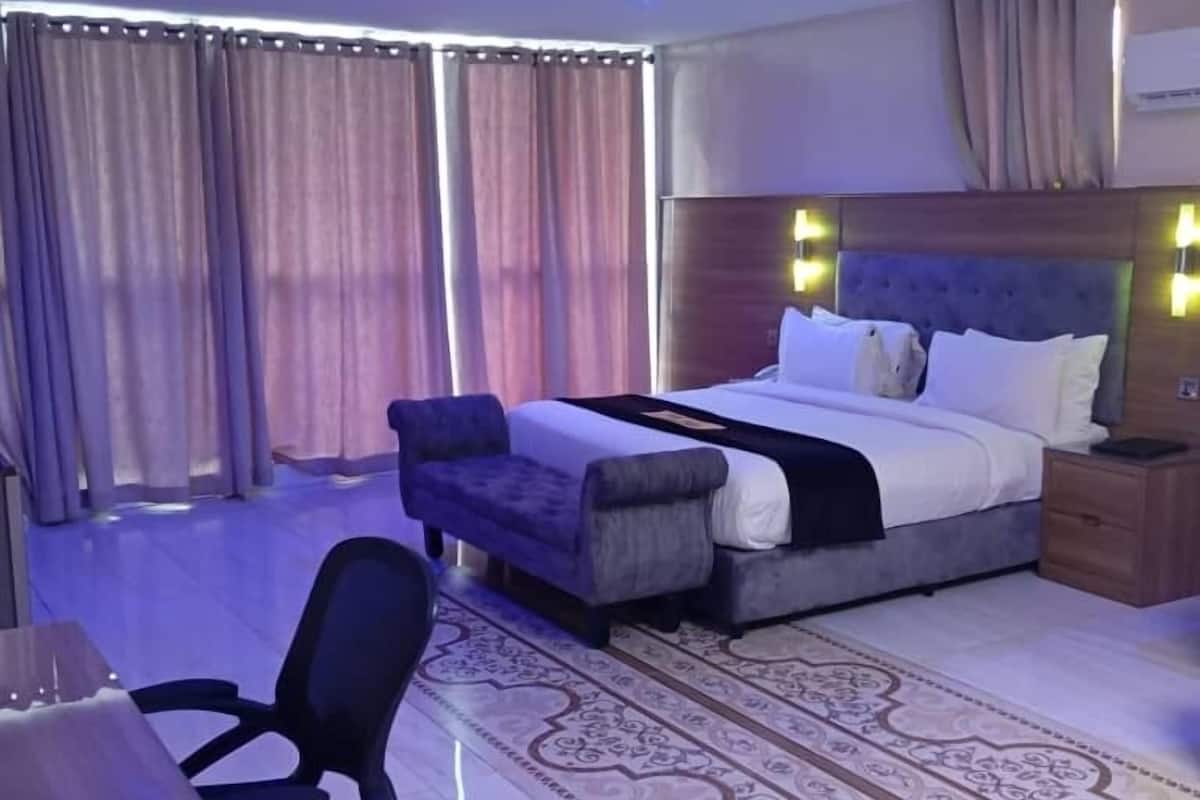 Een hotelkamer met een bed, een bureau, een stoel en een kamerbreed tapijt met dessin.