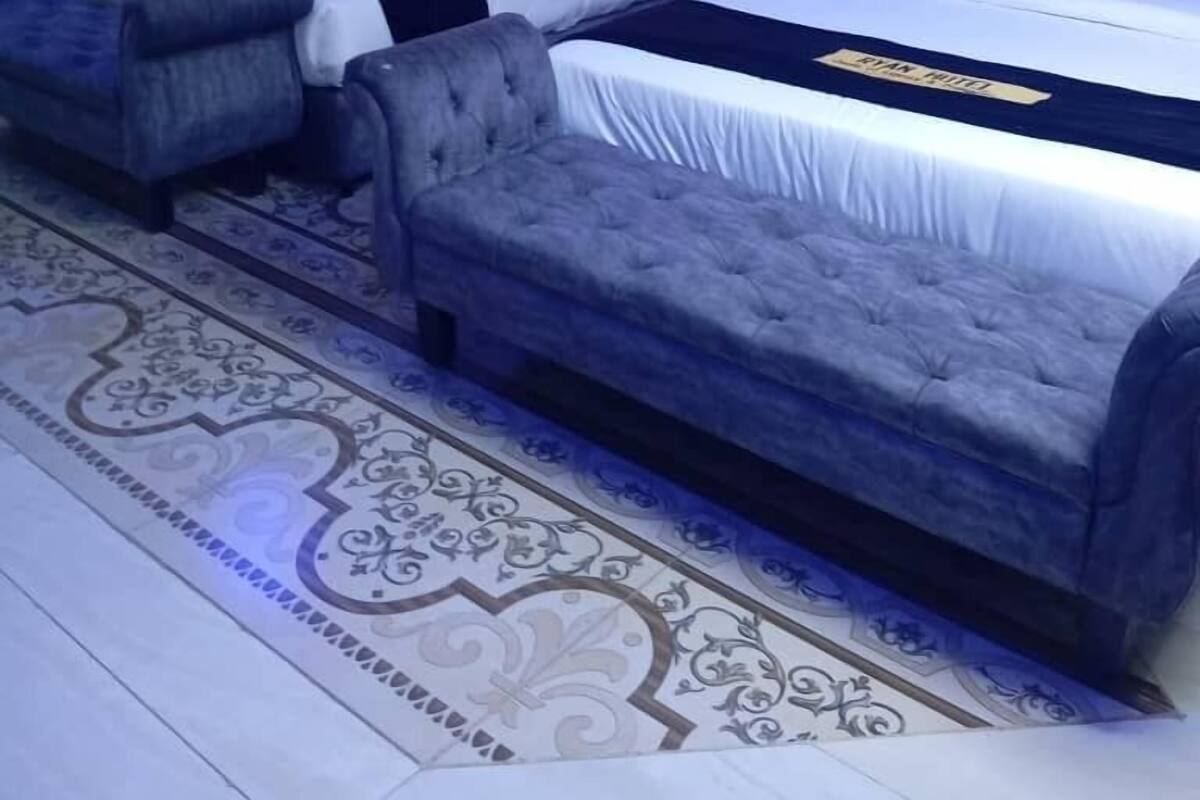 Een hotelkamer met twee bedden, een bank en een kamerbreed tapijt met dessin.