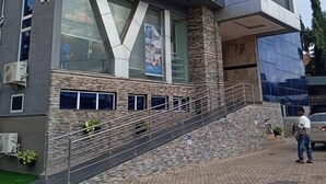 Ein modernes Gebäude mit Glasfassade, Steinsockel und einer Treppe zum Eingang.