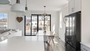 A modern kitchen with a large island, white cabinetry, and a black refrigerator.