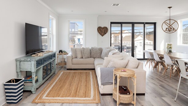 A modern living room with a sofa, television, and a dining area with chairs.
