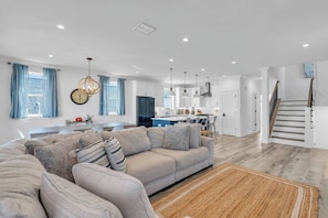 A modern living room with a sofa, a rug, and a kitchen in the background.