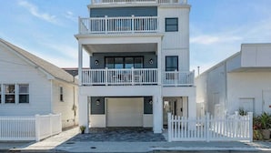 A two-story residential building with a garage, white railings, and a small balcony.