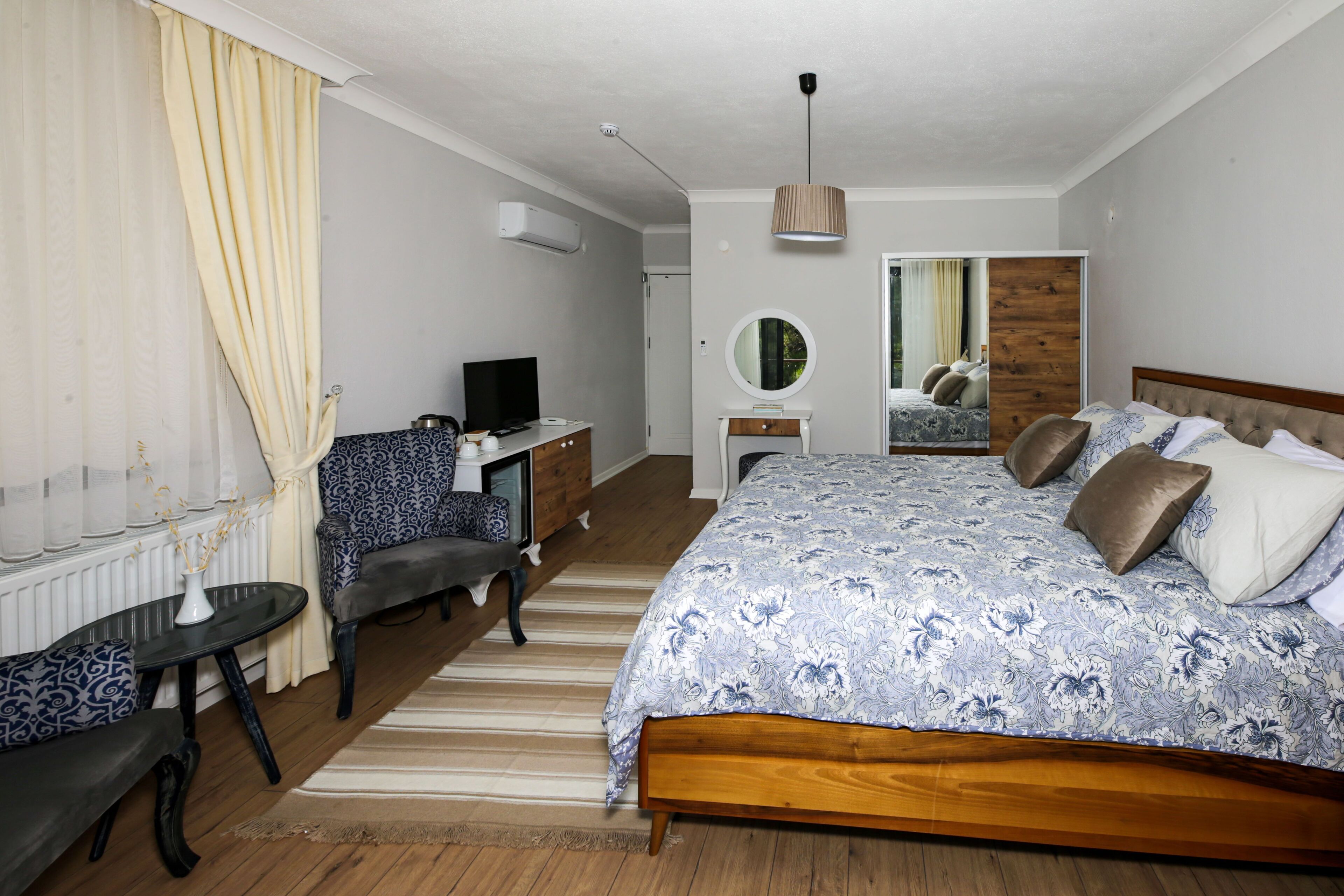 Ein Schlafzimmer mit einem großen Bett, einem Schreibtisch, einem Stuhl, einem Spiegel und einer Heizung.