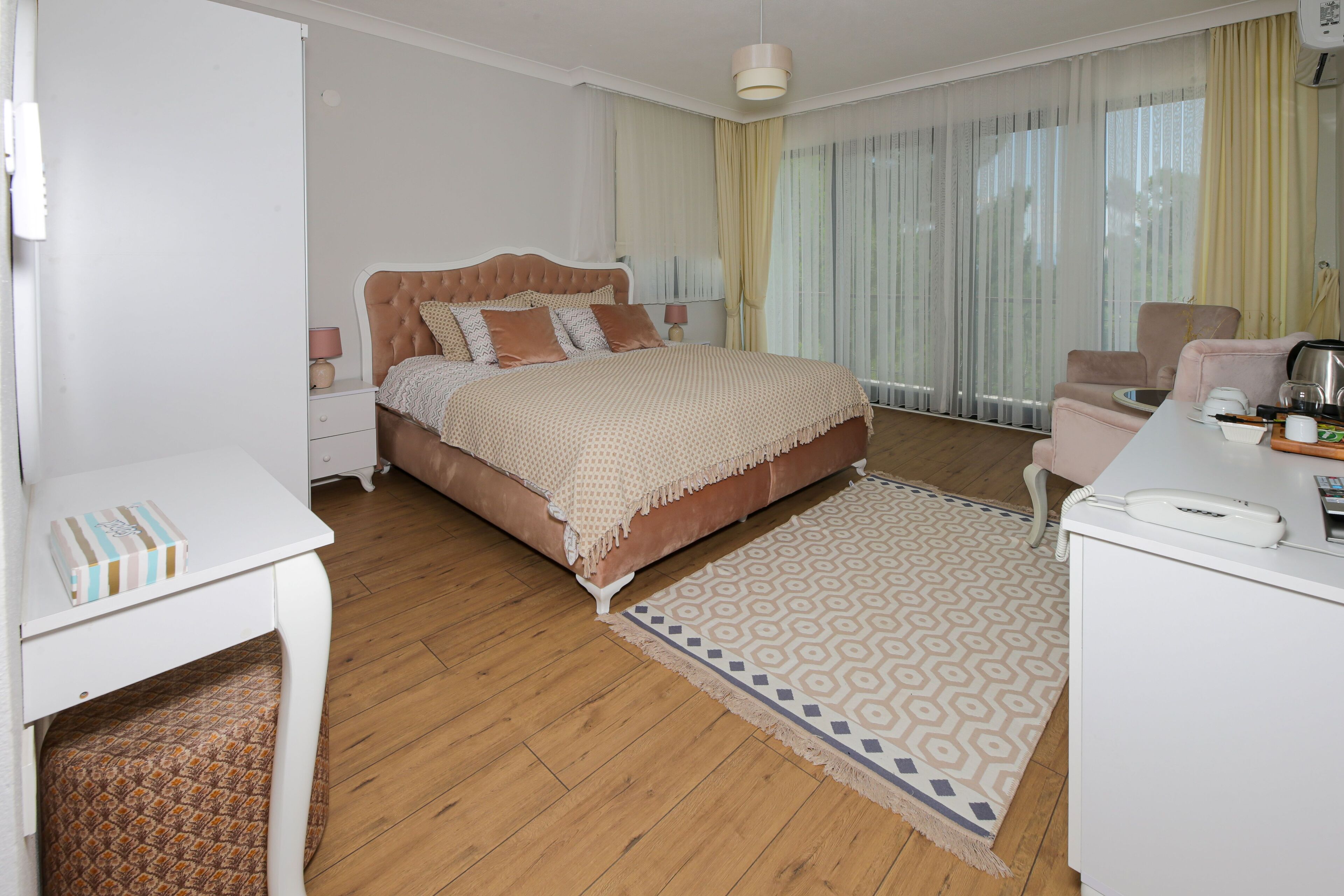 Une chambre bien rangée, avec un lit, une table de chevet, une chaise et un bureau avec un téléphone.