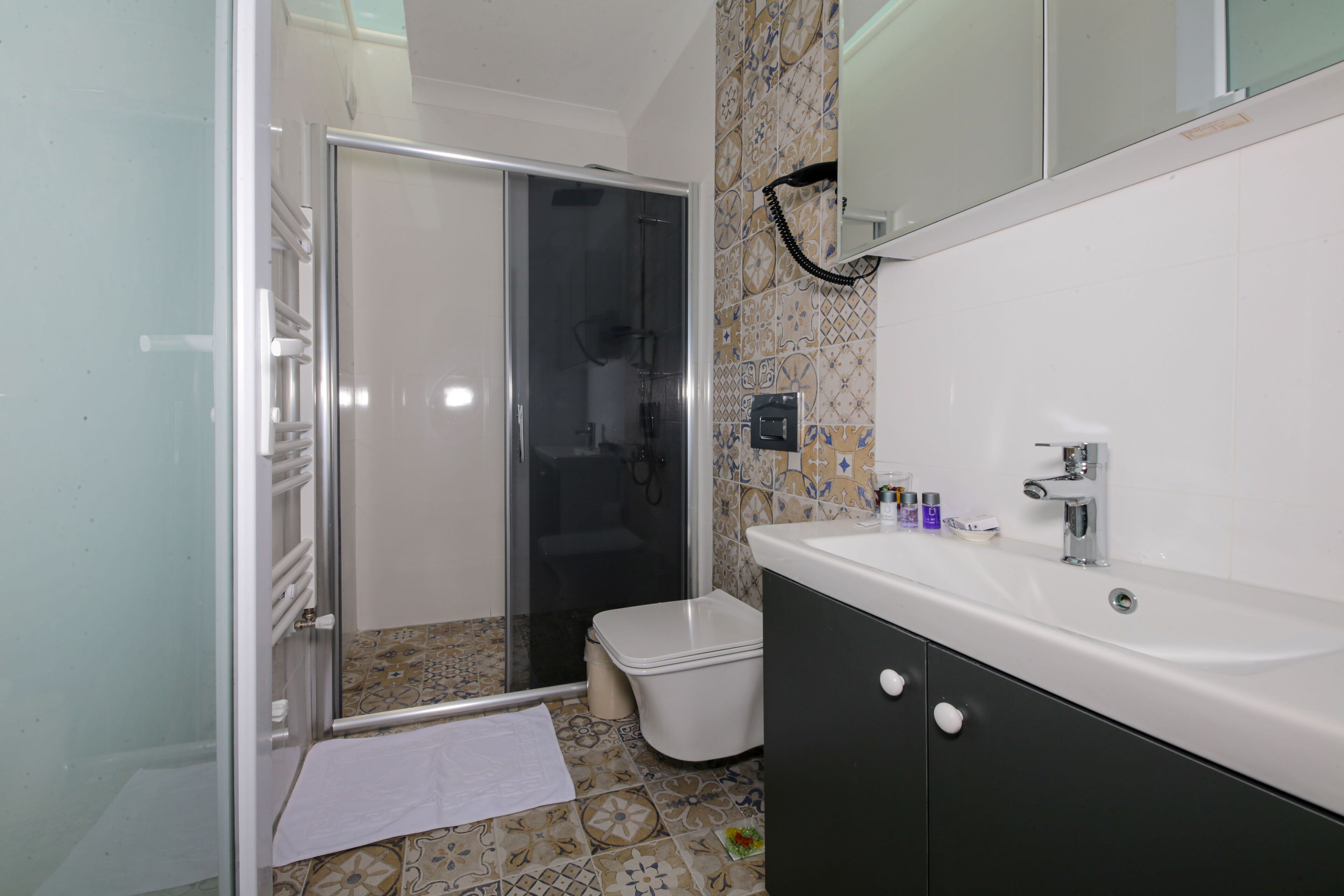 Un baño con ducha, inodoro, lavamanos y paredes con azulejos.