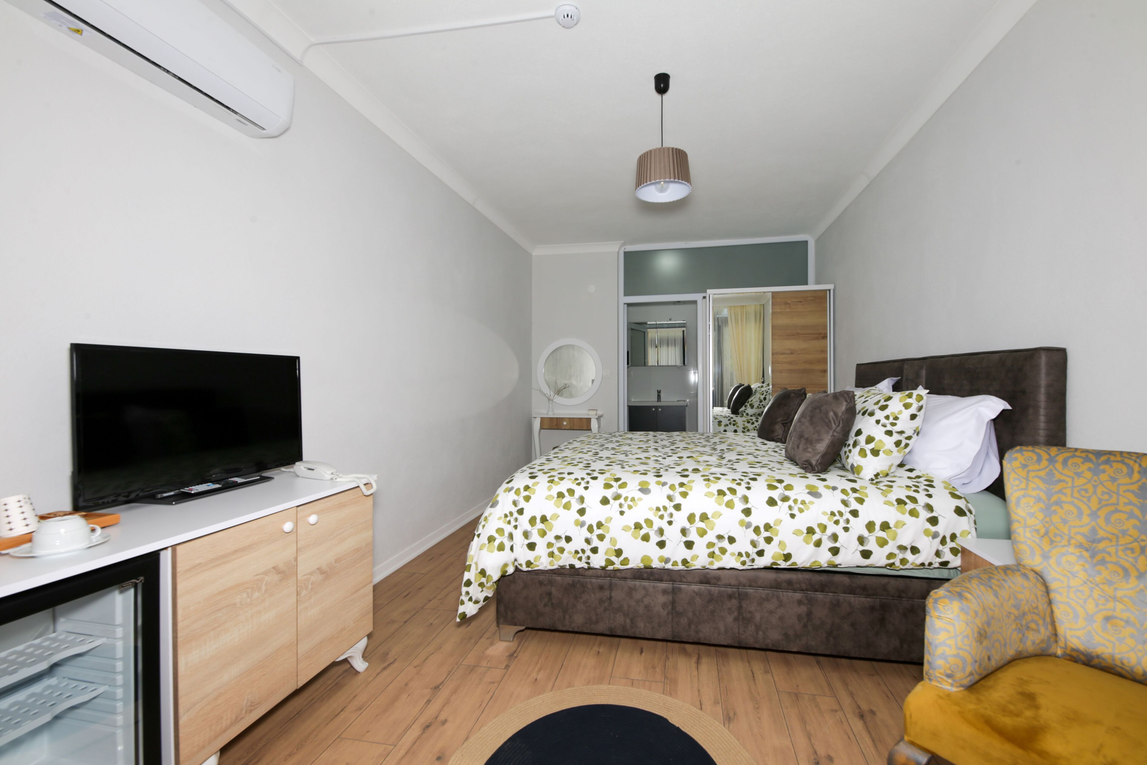 A bedroom with a bed, a TV, a wardrobe, and a desk.