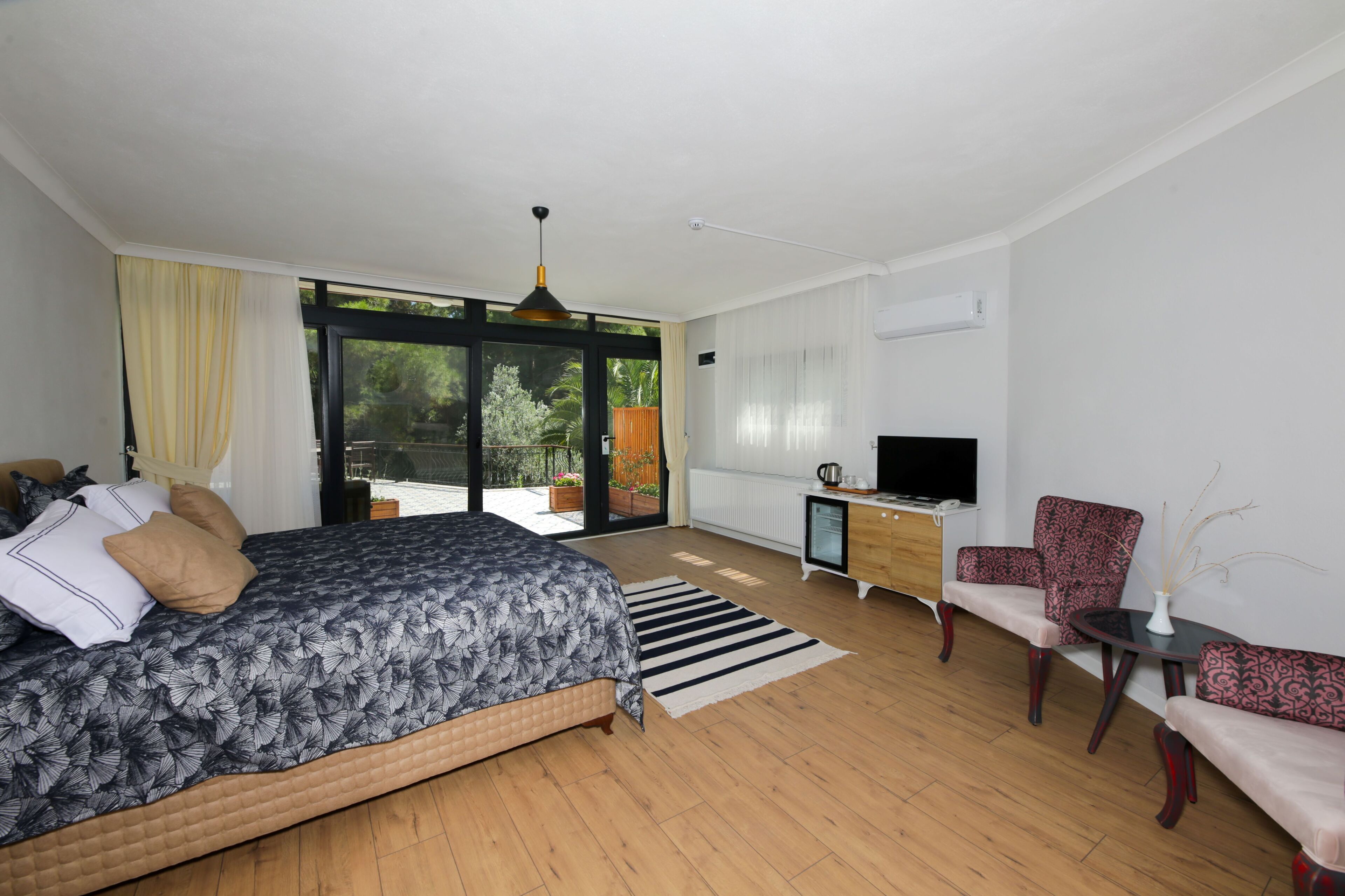Un dormitorio moderno con una cama grande, un televisor, un escritorio y una silla.