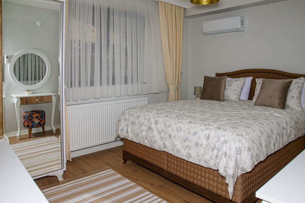 Une chambre à coucher avec un lit, une table de chevet, un miroir et un radiateur.
