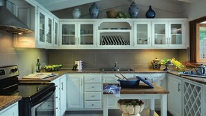 A modern kitchen with white cabinetry, a wooden countertop, and a built-in stove. - 4 Bedroom Golf Lake Front Villa in Casa de Campo (La Romana)