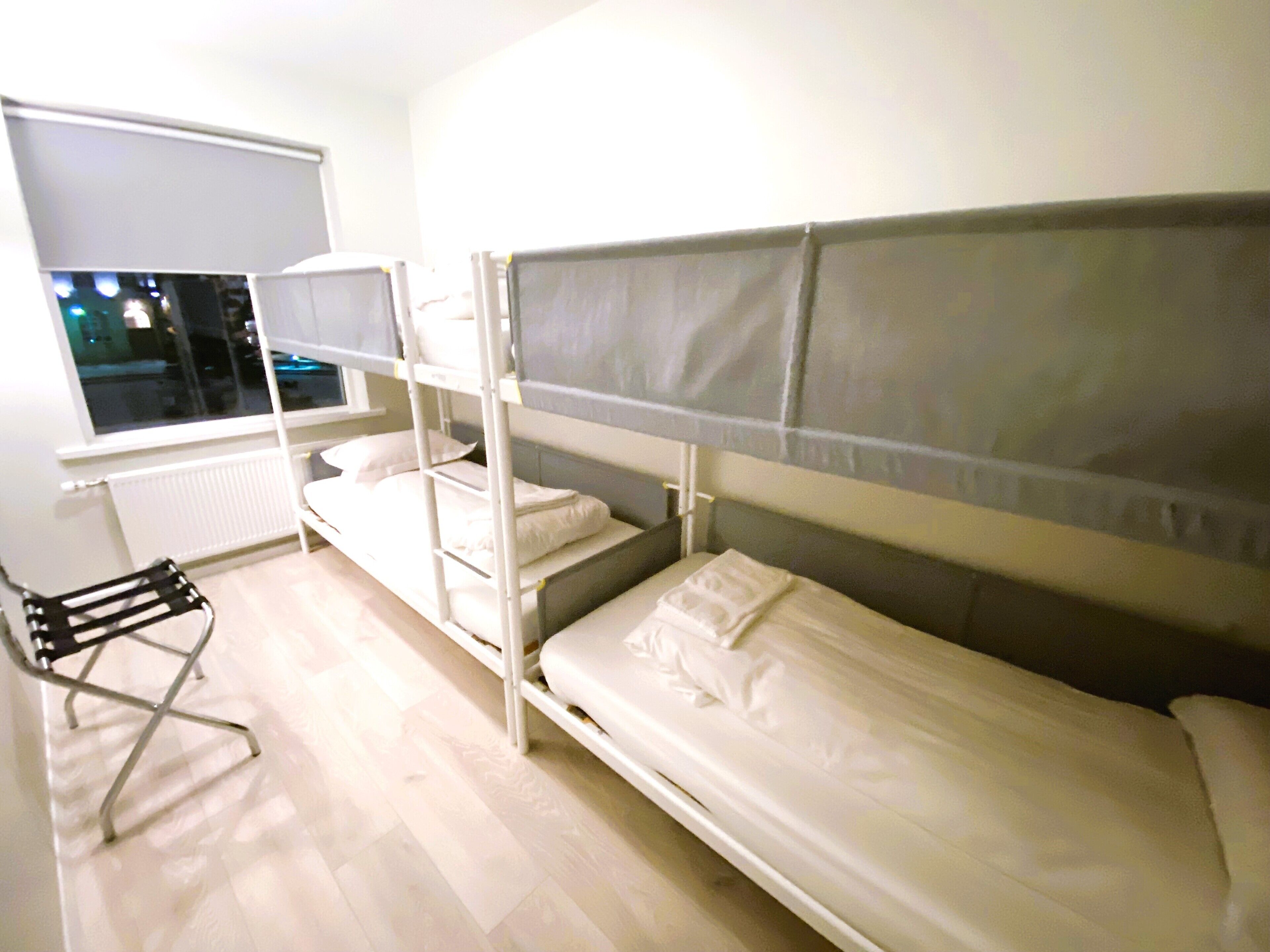 Un dormitorio con literas, un radiador, una ventana y una silla.