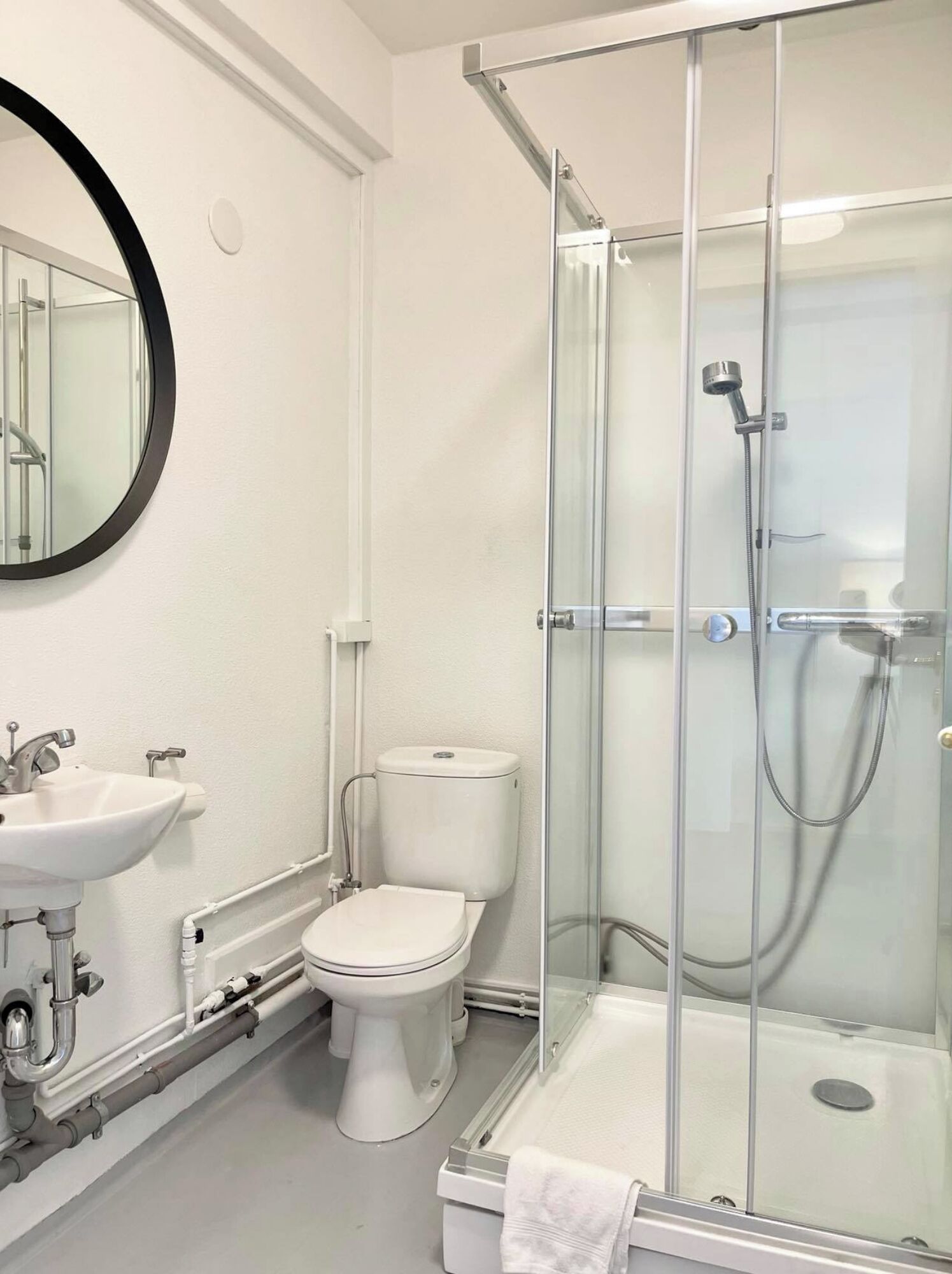 A modern bathroom with a toilet, sink, and glass-enclosed shower.