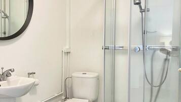A modern bathroom with a toilet, sink, and glass-enclosed shower.