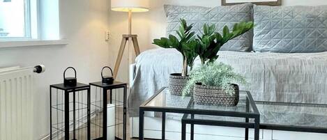 A modern bedroom with a bed, a bedside table, a floor lamp, and a window.