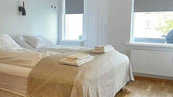 Un dormitorio con dos camas, un radiador y una ventana con persianas.